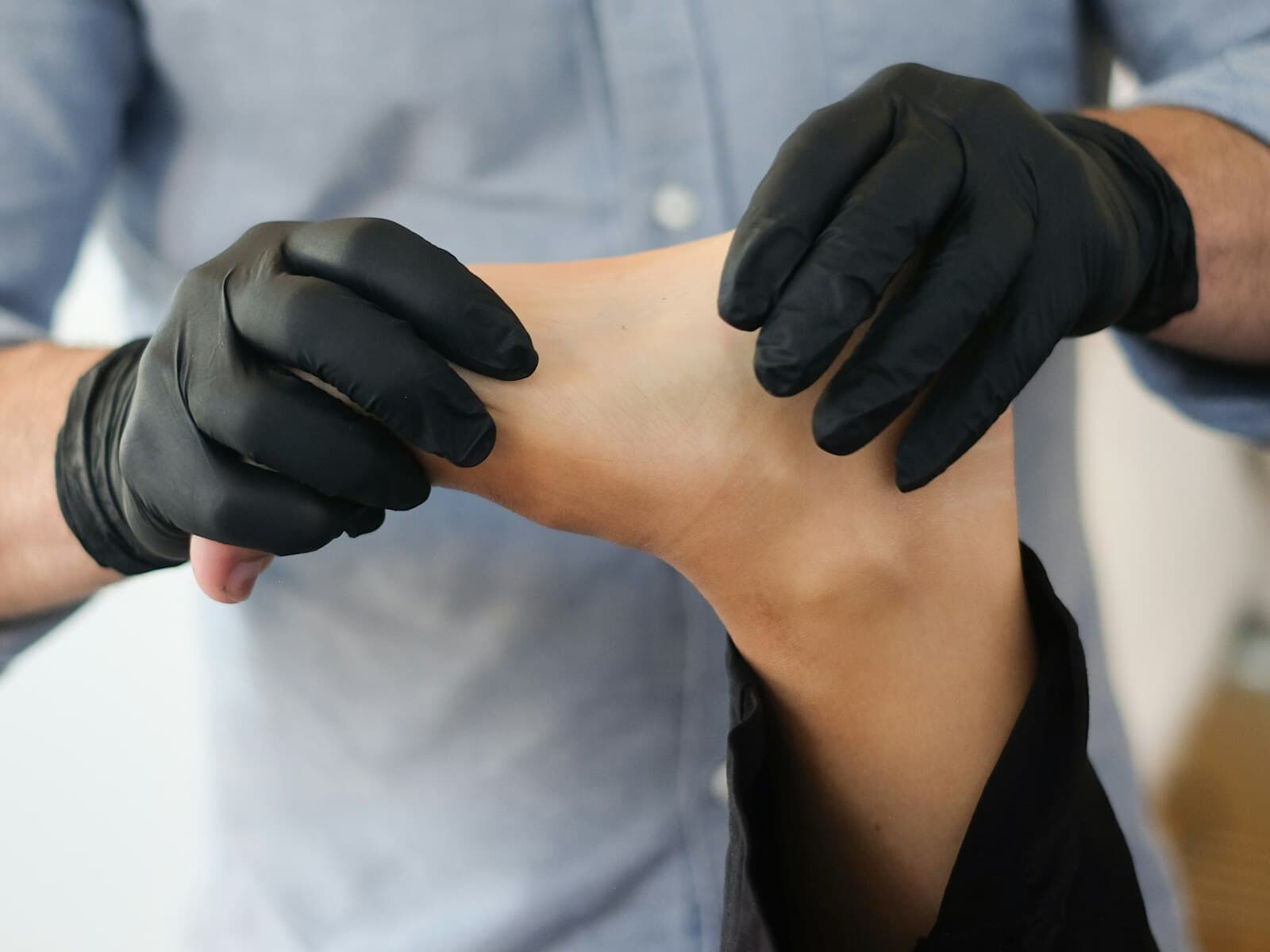 A gloved foot-care nurse examining a patient's foot.